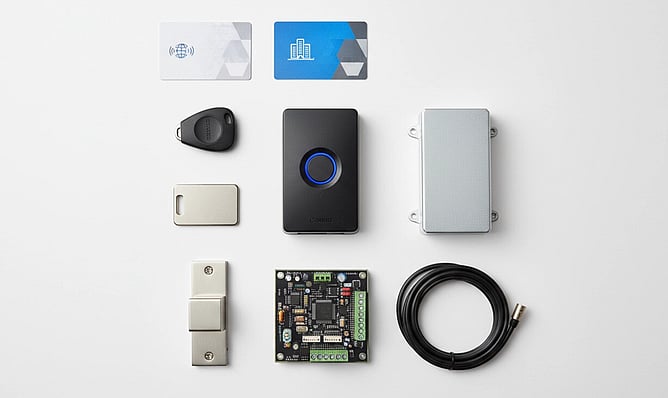Swipe card access control kit laid out on a white background, including access cards, key fob, reader, controller board, door lock, enclosure, and cable