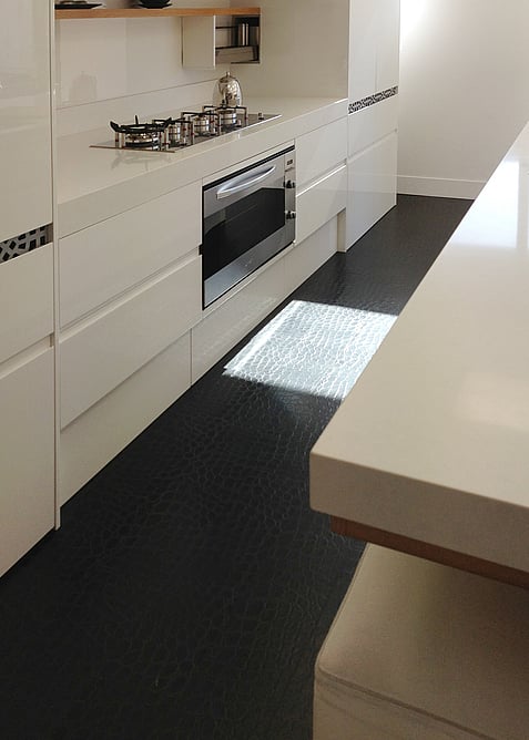Black leather floor showing leather texture in a kitchen with white cabinets.
