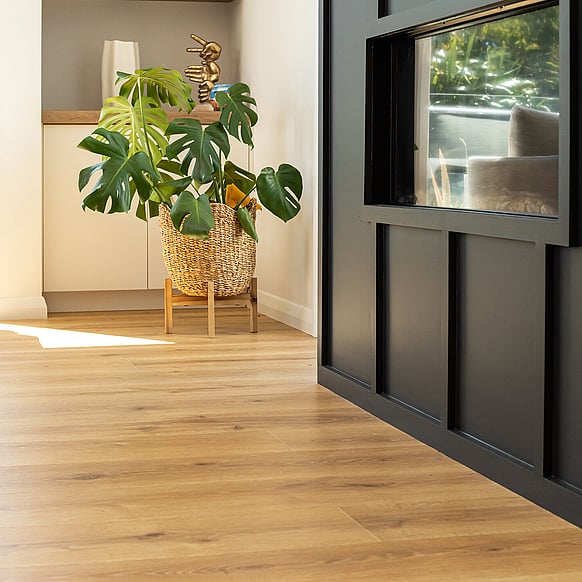 A light beige laminate floor in a kitchen, dining room and living area. Living area has a bright yellow couch.