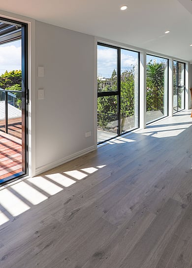 A medium coloured wood laminate floor in a grey and wood kitchen. The flooring shows more grains and knots.