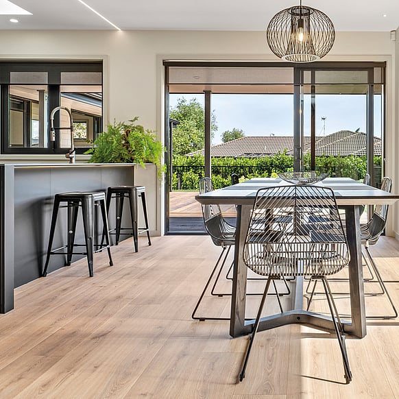 Open plan kitchen and dining room with light brown laminate flooring.
