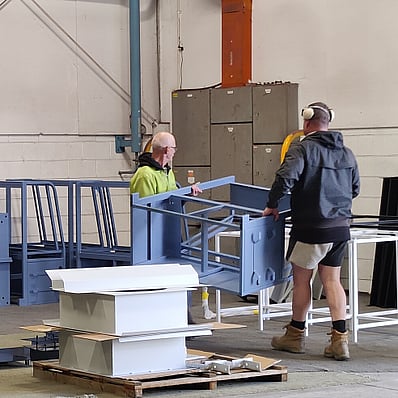 Photo of team members at HIPC carrying recently powder coated items through a warehouse