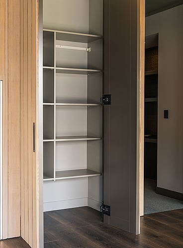 Built-in hallway cupboard with doors open to show solid shelving.