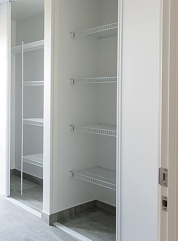 Laundry cupboard wire shelving with sliding doors open.