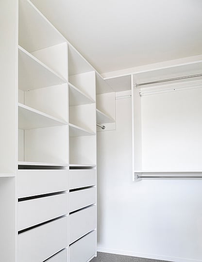 White walk-in wardrobe system with drawer, shelves and handing rails.