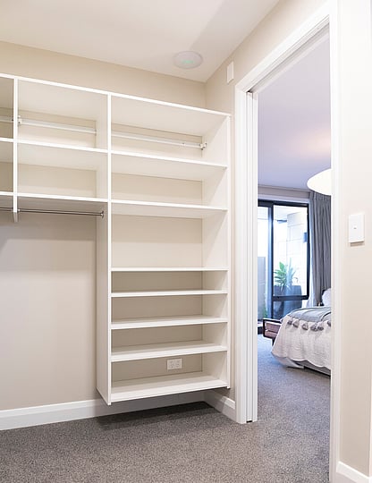 White fitted wardrobe system with solid shelving.