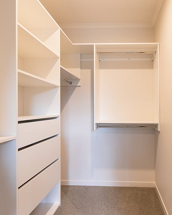 Walk-in wardrobe system in white showing drawers, open shelves and hanging rails