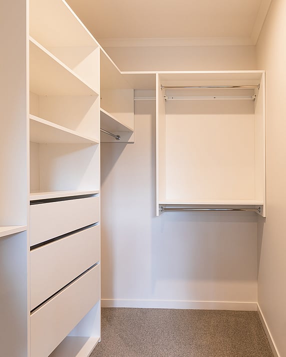 Walk-in wardrobe system in white showing drawers, open shelves and hanging rails