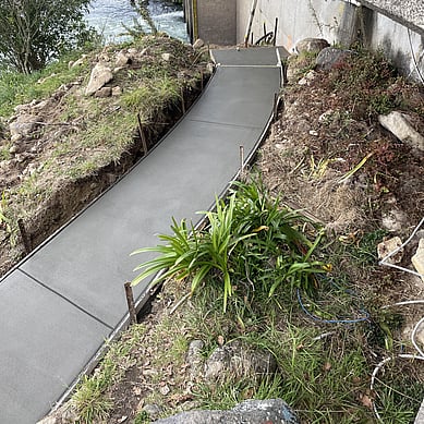 dark grey concrete footpath leading down river bank