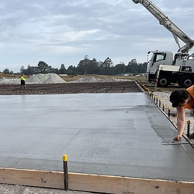 large concrete floor being laid by concrete workers