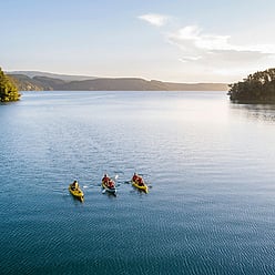 Small group kayaking on Rotorua Lake as the sun beings to set