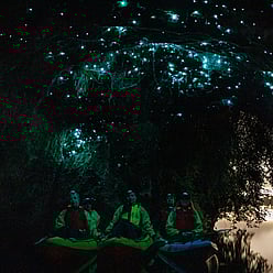 Small group sitting in kayaks below glow worms