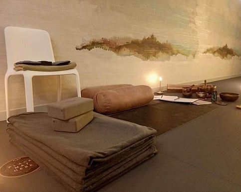 a photo of a yoga class set-up in the Earth Studio, featuring a yoga mat. blanket, bolsters, and blocks