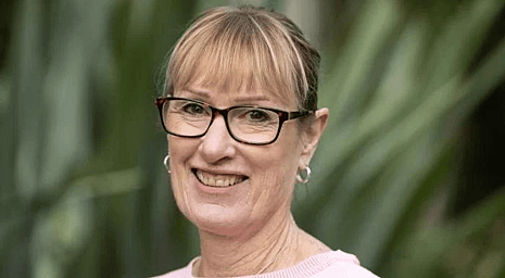 A portrait photo of Chrissie Martyn from Beyond Therapy, standing in front of green grass backdrop