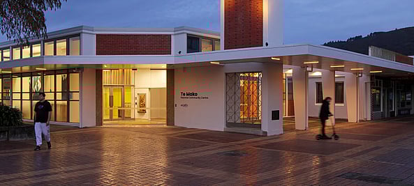 A photo of Te Mako from outside in the evening, the lights are shining through the front doors.