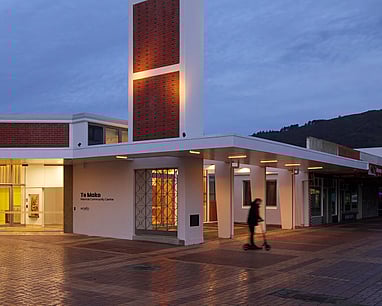 A photo of Te Mako from outside in the evening, the lights are shining through the front doors.