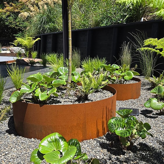 natural rock and native plant landscaping in a Rotorua home with pavers and wooden steps