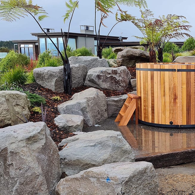 natural rock and native plant landscaping in a Rotorua home with pavers and wooden steps