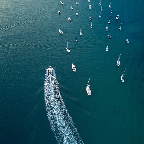 Birds eye view of a boat motoring past other boats moored 