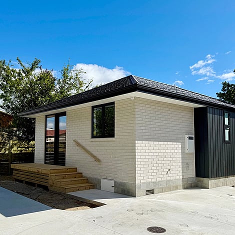 Image of a soft neutral stone small building with wooden step entrance on Clarkin Road. Built by Ardent Building Developments, Hamilton. Waikato, New Zealand.