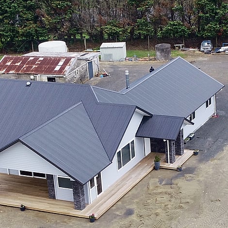 Image of white cladded new home with stone pillars on Te Wharepu Road. Built by Ardent Building Developments, Hamilton. Waikato, New Zealand.