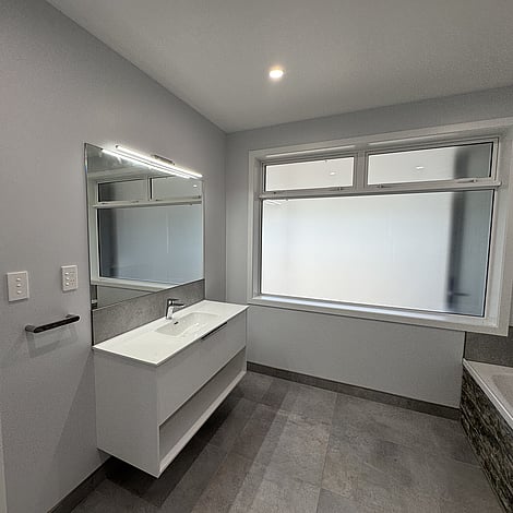 Image of tiled floor bathroom with white cabinetry in Te Wharepu Road new home build. Built by Ardent Building Developments, Hamilton. Waikato, New Zealand.