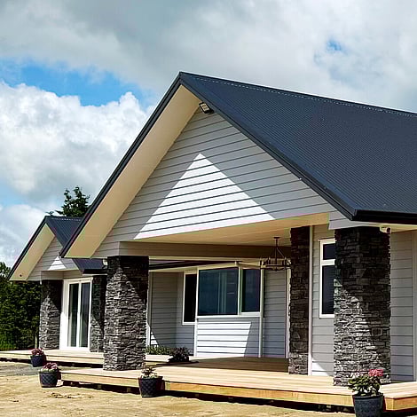 Image of white cladded new home with stone pillars on Te Wharepu Road. Built by Ardent Building Developments, Hamilton. Waikato, New Zealand.
