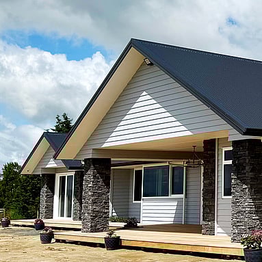 Image of white cladded new home with stone pillars on Te Wharepu Road. Built by Ardent Building Developments, Hamilton. Waikato, New Zealand.