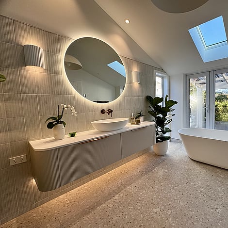 Image of curved finger tiled cabinet in soft grey, with white basin and circle mirror in this Bedford Road bathroom extension. Built by Ardent Building Developments, Hamilton. Waikato, New Zealand.