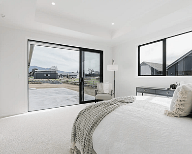 Image of natural light filled master bedroom with neutral styling opening with outlooks in Collinson Street, Pirongia new home, by Waikato residential builders Whitechurch Construction Limited.