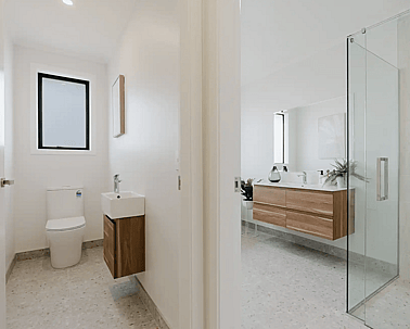Image of modern neutral toilet and bathroom with timber cabinetry and pale grey tiling in Collinson Street, Pirongia new home, by Waikato residential builders Whitechurch Construction Limited.