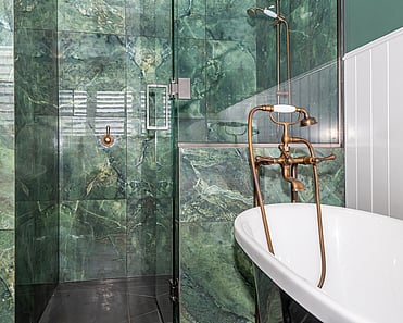 Close up image of claw bath and green marble tiled shower in renovated heritage bathroom. Renovated by local Te Awamutu residential builders, Whitechurch Construction.