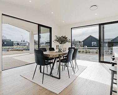Image of natural light filled dining area with modern table and chair styling in Collinson Street, Pirongia new home, by Waikato residential builders Whitechurch Construction Limited.