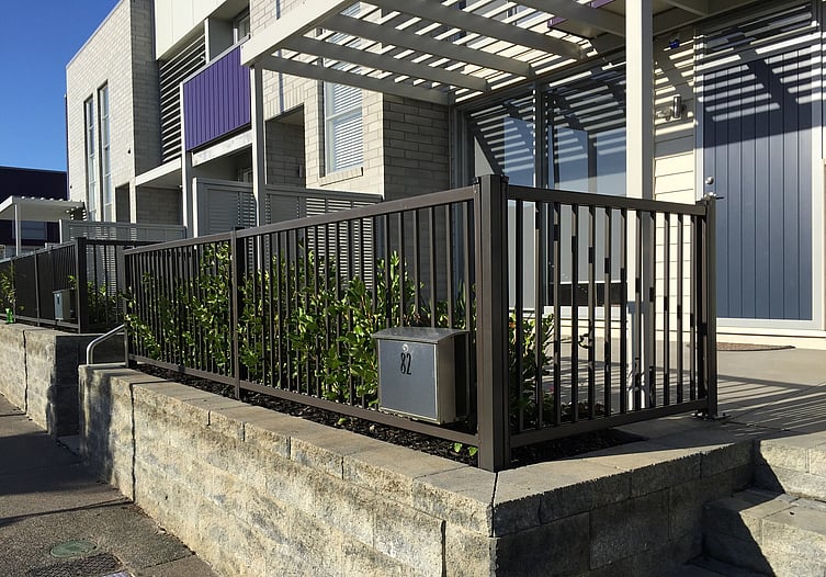 photo of a high wall, with a Moduline barrier fence for protection from falling, and a row of planted shrubs for garden beauty
