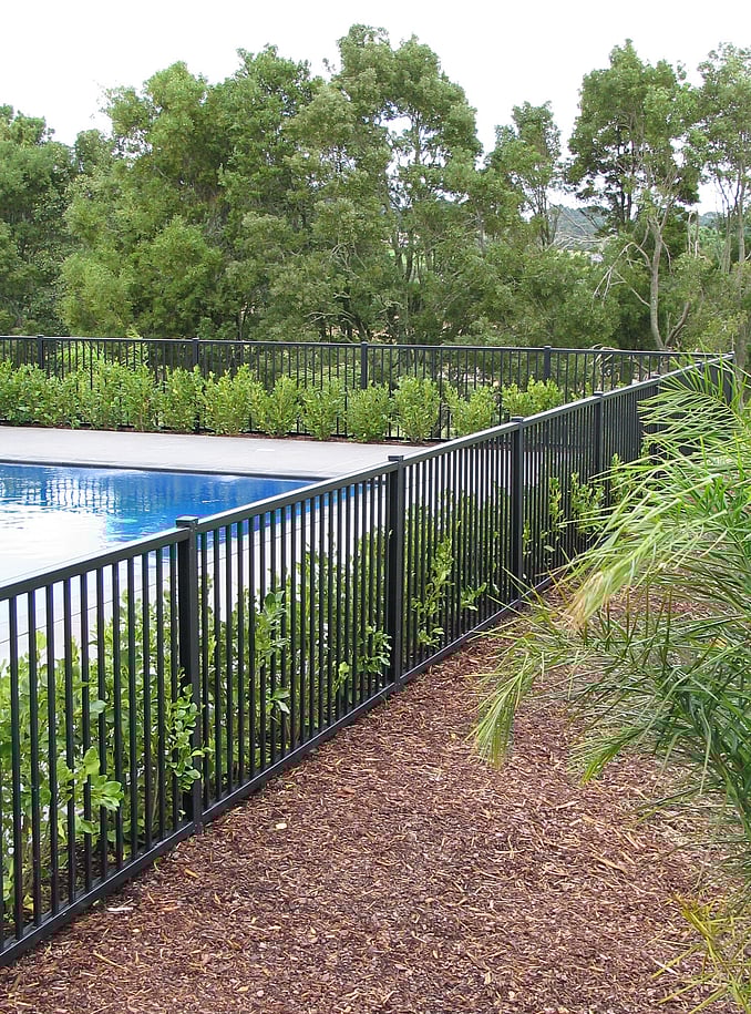 photo of a beautiful pool surrounded by garden and trees with a Moduline PoolSide fence