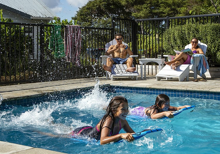 The young family enjoys a sunny day by pool, the kids having a blast, with Moduline PoolSide pool fencing keeping them safe and secure