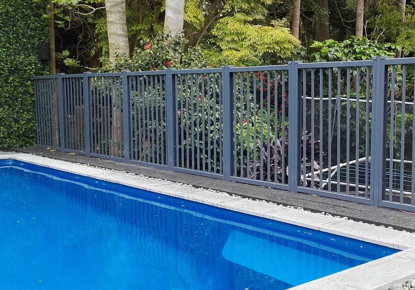 photo of a pool with beautiful garden surround, and Moduline barrier fencing to provide a safety barrier over the high drop