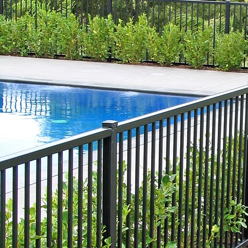 photo of a beautiful pool surrounded by garden and trees, with Moduline PoolSide fencing for safety