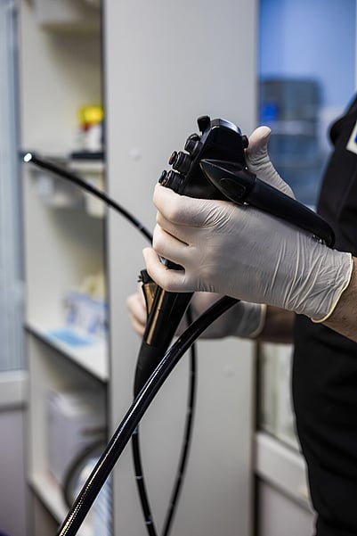 A vet preparing an endoscope for a medical procedure.