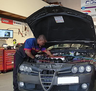 Technician fixing car whilst refrigerant machine is attached