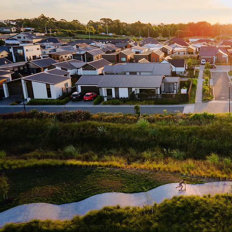 drone shot of child riding a scooter with houses in the background