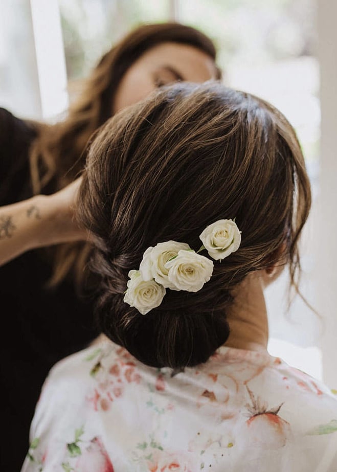 Georgie styling a beautiful low bun updo with white flowers tucked in.