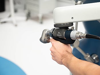 X-ray illustration of a side view of a human knee joint, showing the femur, tibia, and patella, against a dark background.