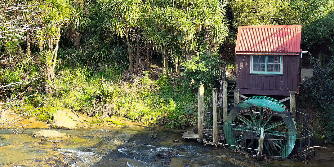 A side view of the river, water wheel and building