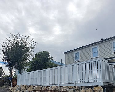 White timber fence above rock retaining wall in residential backyard