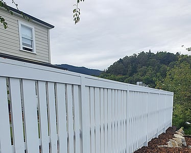 Long white timber fence along boundary with fresh landscaping