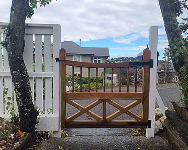 Custom timber gate with white fence in Nelson garden