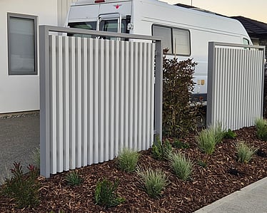 Modern white vertical slat privacy screen beside driveway with planting