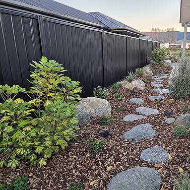 Stepping stone path with planting and rock features along fence line Nelson