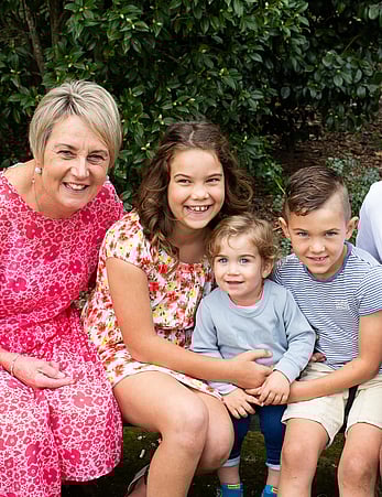 Grandmother smiles next to her three young grandchildren